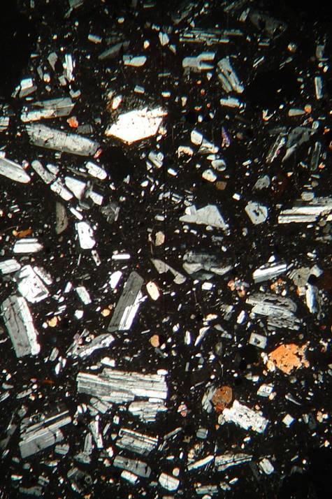 aliran; fenokris terdiri dari plagioklas, piroksen, biotit, dan mineral opak; tertanam dalam masadasar mikrolit plagioklas, opak, dan gelas; setempat ditemukan struktur vesikuler.