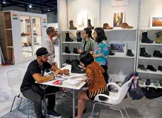 Produsen alas kaki berdiskusi dengan pembeli potensial. Pembeli yang tertarik membeli sepatu di FOOTWEAR SOURCING pada pameran dagang MAGIC. embelian alas kaki di Indonesia.