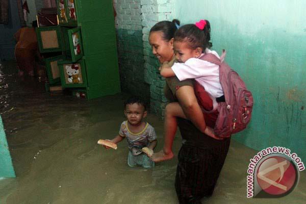 6. Seorang kakak menggendong adiknya yang mau sekolah dalam melintasi genangan air yang merendam rumahnya saat Banjir Besar.